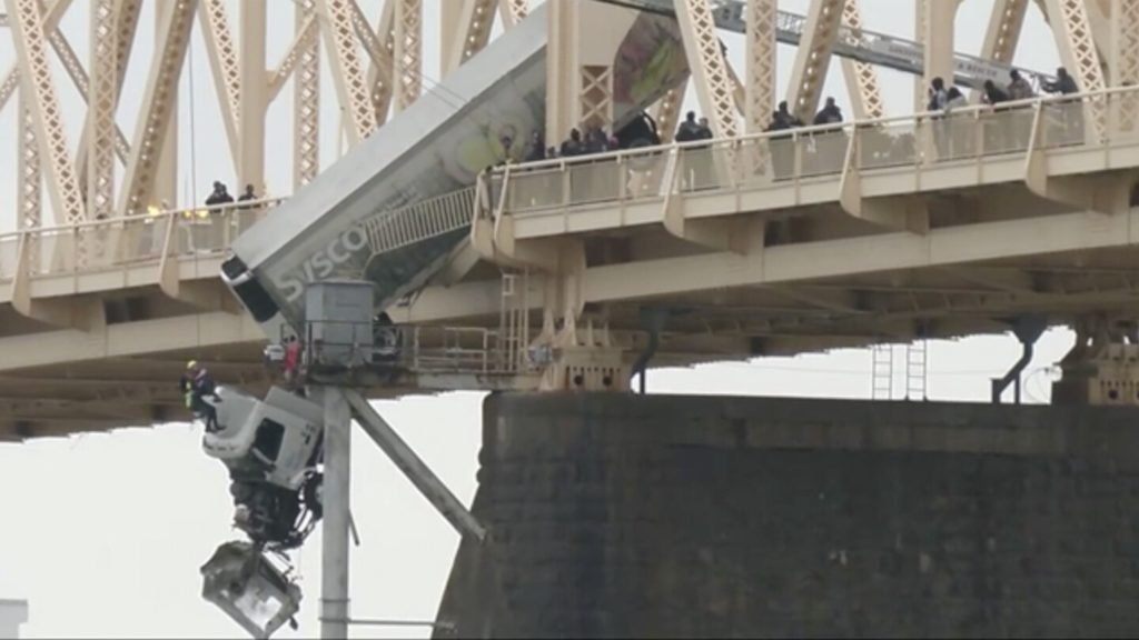 Truck driver pulled to safety after crash leaves vehicle dangling over bridge across Ohio River - The Associated Press
